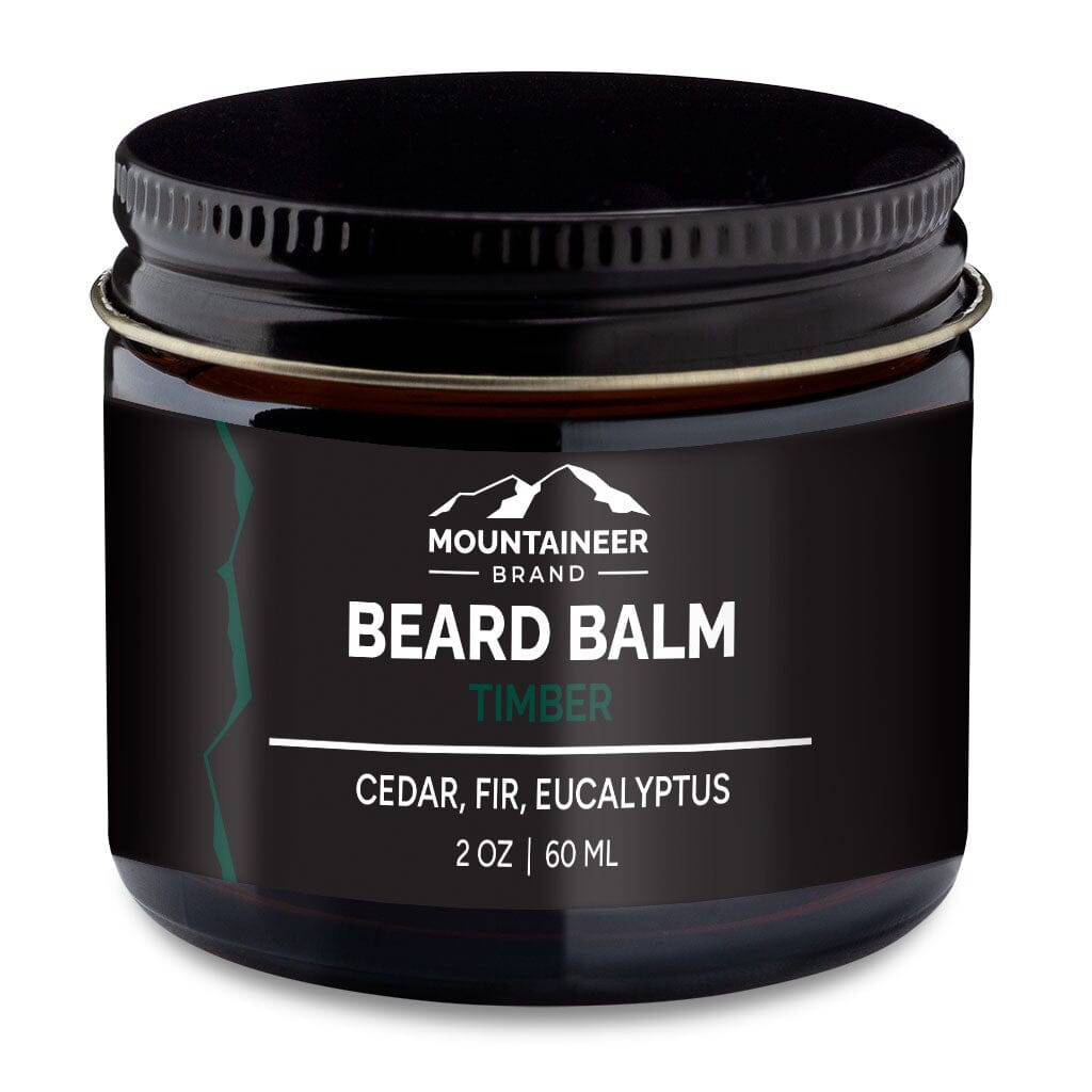 A jar of Mountaineer Brand Products beard balm labeled "timber" with cedar, fir, and eucalyptus natural essential oils, 2 oz or 60 ml size.