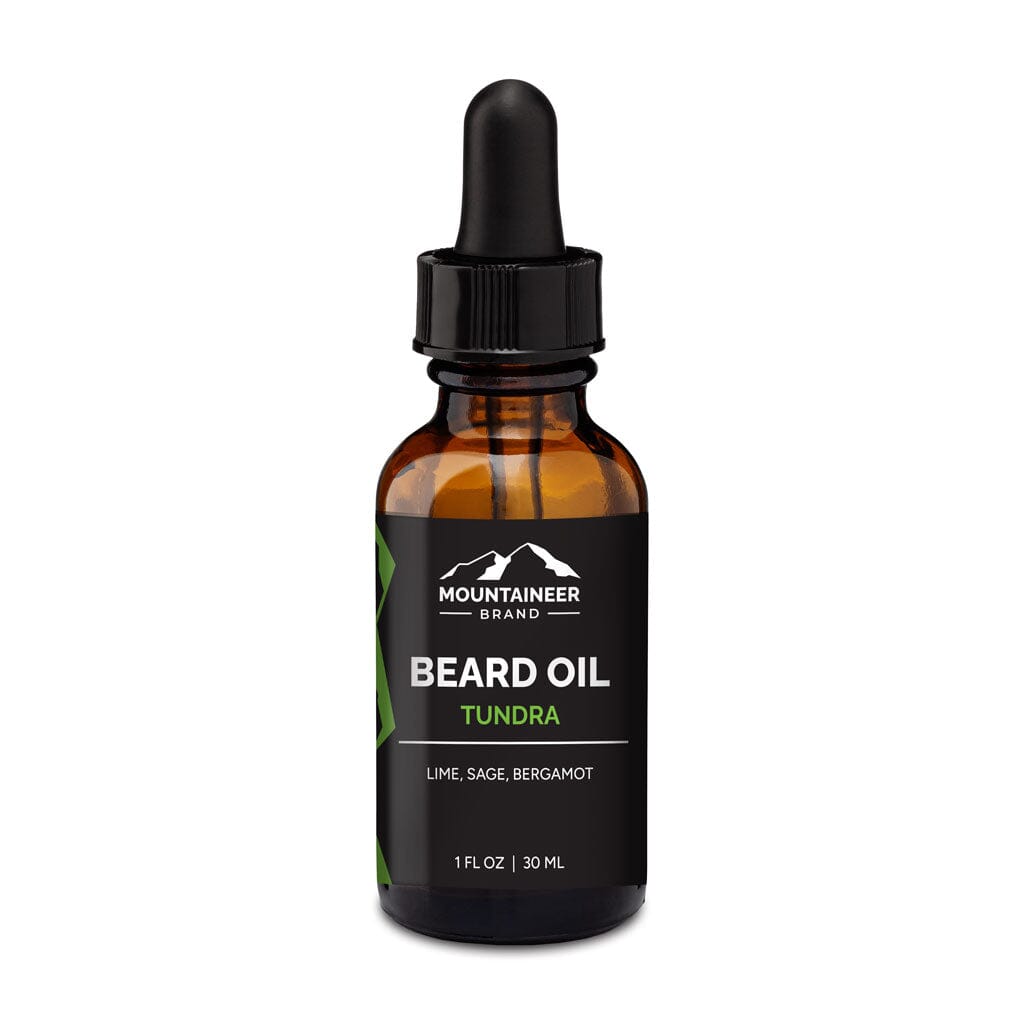 A bottle of Mountaineer Brand Products Natural Beard Oil labeled "Tundra" with lime and sage fragrance, featuring essential oils and a dropper, isolated on a white background.