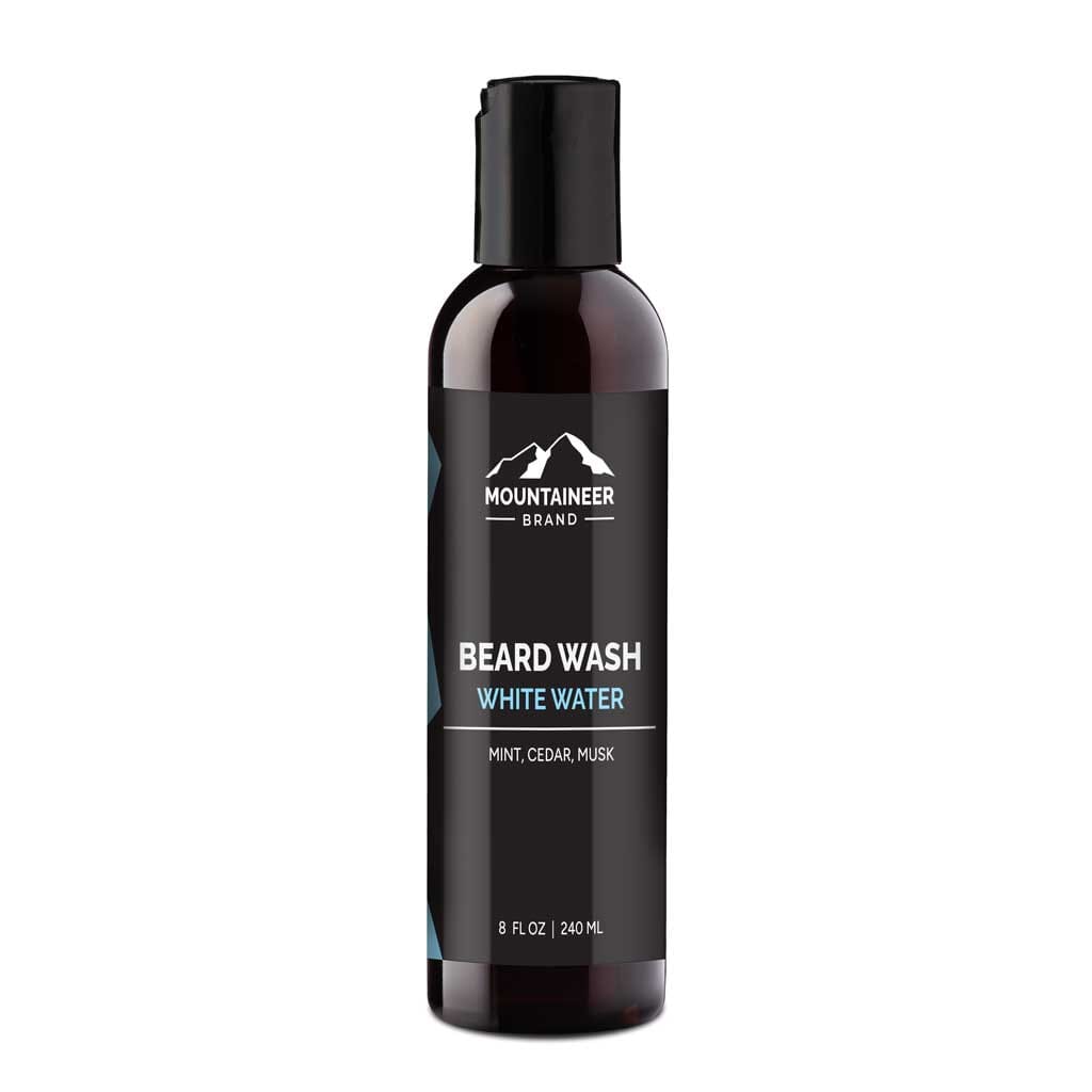 Bottle of Mountaineer Brand Products Beard Wash labeled "white water" with mint, cedar, and musk scents, featuring natural ingredients, isolated on a white background.