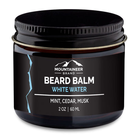 A jar of Mountaineer Brand Products beard balm labeled "white water" with mint, cedar, and musk scents from natural essential oils, containing 2 oz (60 ml) of Natural Beard Balm.