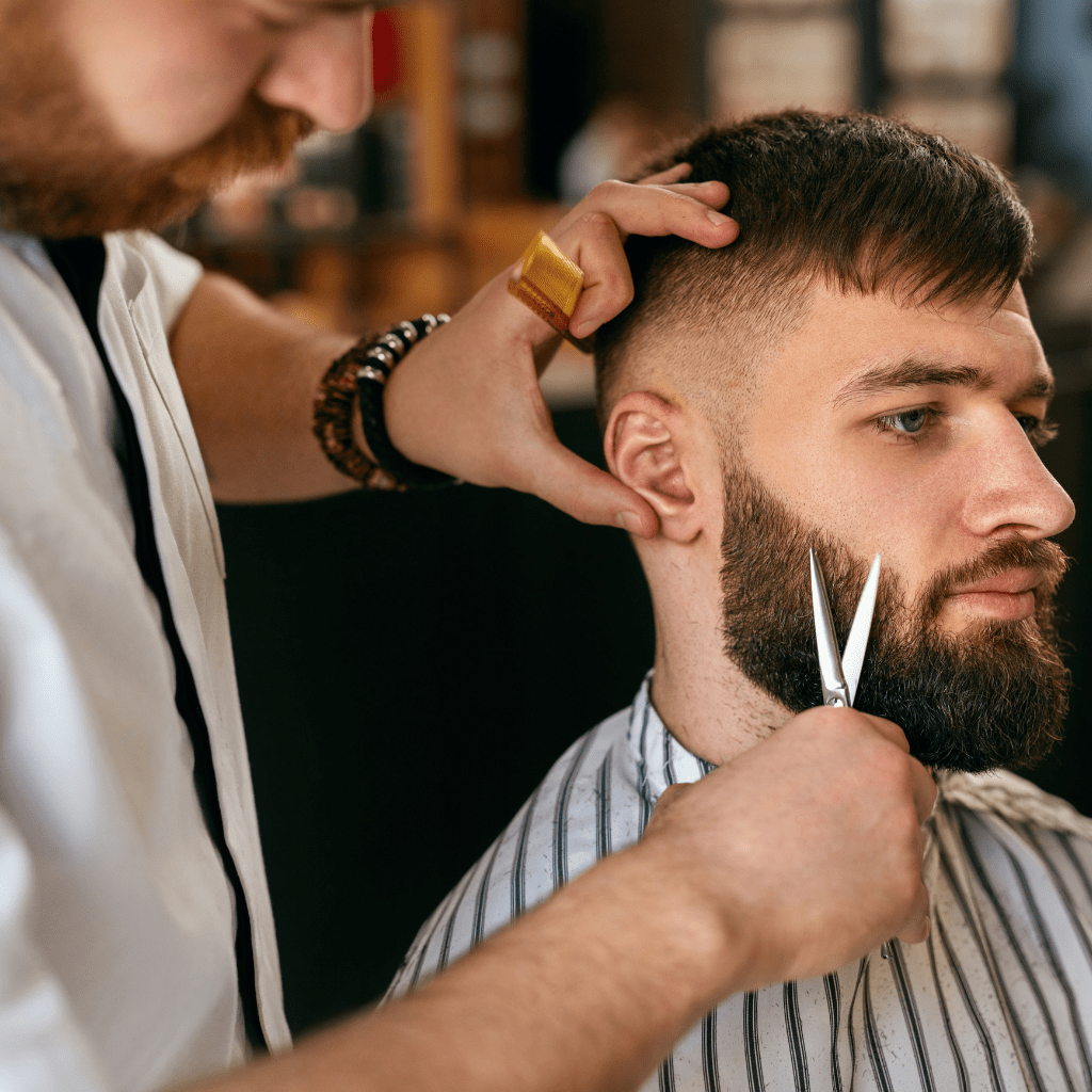Using Mountaineer Brand Products' Stainless Steel Beard & Moustache Scissors, a barber expertly trims a man's beard.