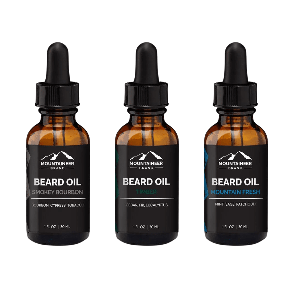 Three bottles of premium quality Mountaineer Brand Products beard oil in different scents: smokey bourbon, timber, and mountain fresh.