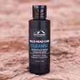 A bottle of Mountaineer Brand Products' Bald Head Cleanse with natural ingredients on a textured background.