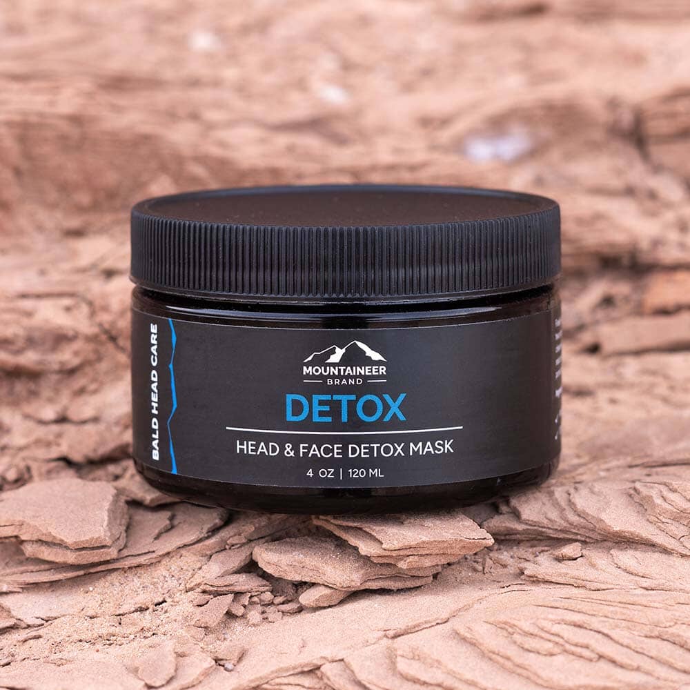 A jar of Mountaineer Brand Products' Bald Head Detox Mask for head and face on a dry, cracked earth background.