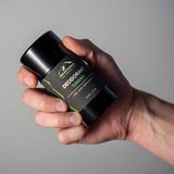 An Natural Deodorant 6-Pack hand holding a bottle of Mountaineer Brand Products organic deodorant, free from harmful chemicals.