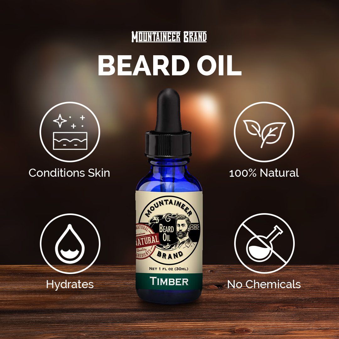 A bottle of Mountaineer Brand Products Natural Beard Oil labeled "timber" on a wooden surface with icons indicating it conditions skin, is 100% natural, hydrates, and contains essential oils.