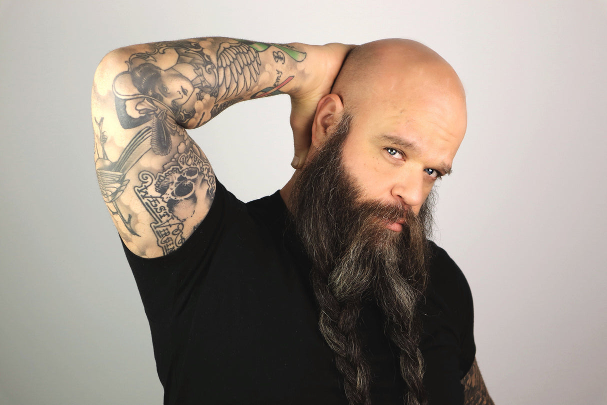 A man with a long beard and tattoos, showcasing his natural radiance using Mountaineer Brand Products' Bald Head Shine Away (PH Balancing Toner).